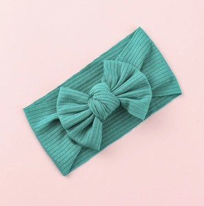 Macro detail of teal knit baby headband featuring a large textured ribbed fabric bow