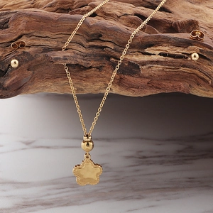 Detailed view of a gold starfish necklace and minimalist stud earrings on marble