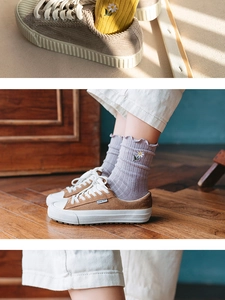 Close-up of yellow and purple socks featuring daisy embroidery and lettuce edge details