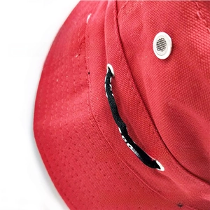 Close-up of red canvas bucket hat with silver ventilation eyelets and adjustable cord