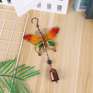 Detail of butterfly wind chime with glass painted orange wings and copper bell on wood