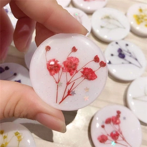 Collapsible round phone grip featuring real red dried flowers and glitter in white resin