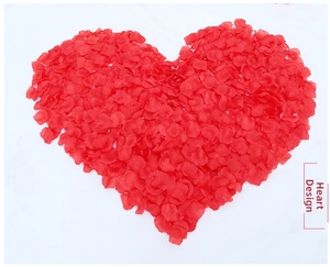 Macro detail of red artificial rose petals arranged in a romantic heart shape on white