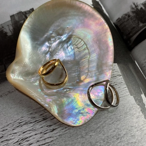 Set of gold and silver minimalist irregular curved rings on a shimmering shell tray