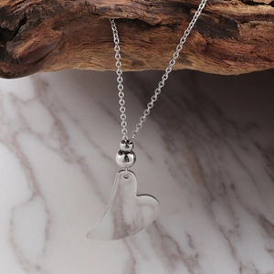 Elegant silver heart pendant necklace with beads on dark wood and marble background