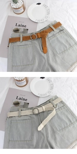 Detail of round buckle woven wax cord belt on light gray high-waist denim shorts