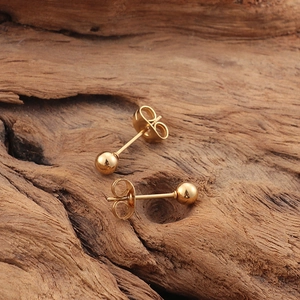 Boucles d'oreilles boules en titane plaqué or 18 carats sur fond bois rustique