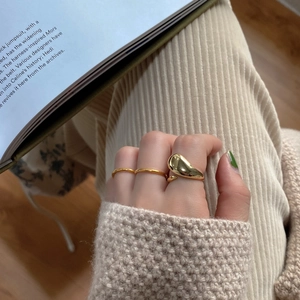 Macro view of gold droplet ring and thin bands set on model's hand with magazine