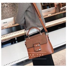 Side view of brown mixed-texture handbag with metal buckle and adjustable strap