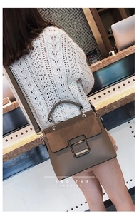 Close-up of khaki leather handbag with suede flap and silver metal square lock on a model