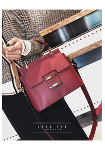 Detail of red matte leather crossbody bag with golden buckle and wide shoulder strap