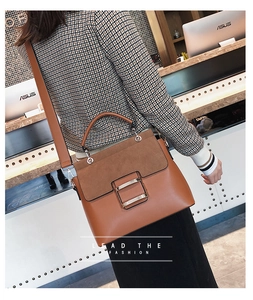 Detail of brown leather and suede stitching bag with a golden square metal buckle