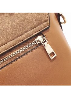 Detailed macro view of gold zipper and textured brown leather on stylish crossbody bag