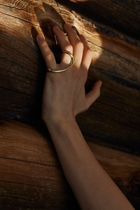 Polished 925 silver wave ring in gold finish on natural wood background shot