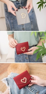 Detail of short leather wallet with gold heart buckle and textured cross pattern