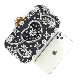 Size comparison of black beaded evening clutch with pearls and crystals next to a phone