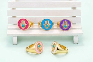 Retro Hamsa hand ringen met kleurrijk emaille en turquoise op een houten standaard