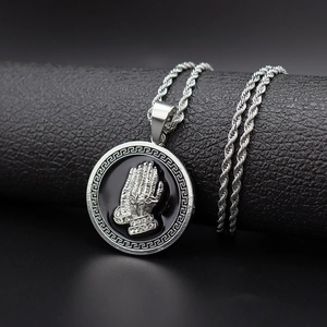 Macro shot of silver hip hop pendant featuring praying hands with diamond accents