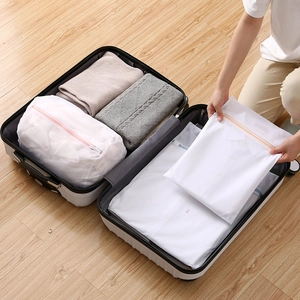 White fine mesh laundry bags with pink zippers organized in a travel suitcase