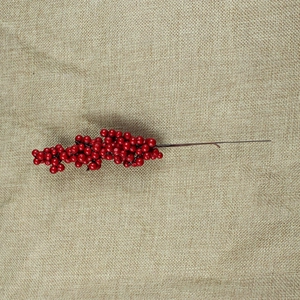 Artificial red berry stems for Christmas DIY crafts on rustic burlap background