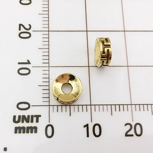 Macro view of golden alloy elephant spacer beads with Greek fret pattern on grid scale
