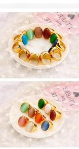 Detail view of oval cat-eye and turquoise stones in gold plating rings on lace