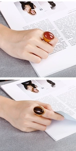 Detailed view of oval tiger eye and gold sand stone rings in polished gold setting