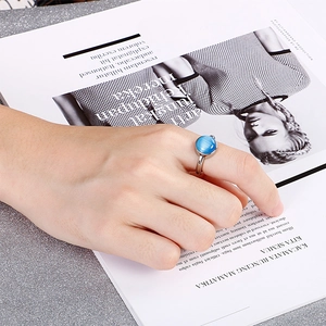 Minimalist silver steel ring featuring a round blue cat-eye stone worn on a hand