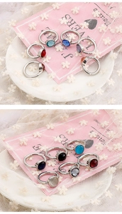 Detail view of colorful cat-eye stones and crystal rings on pink decorative cards