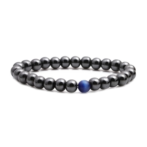 Polished hematite beaded bracelet with a single blue cat-eye stone on white background