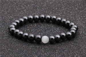 Detailed close-up of a hematite and white cat-eye stone bead bracelet on grey background