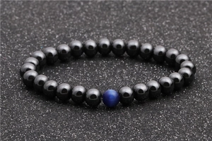 Detailed shot of beaded bracelet with dark grey hematite beads and one blue cat eye stone