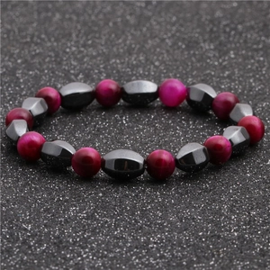 Dettaglio del bracciale con perle rosa e ematite sfaccettata su sfondo nero brillante