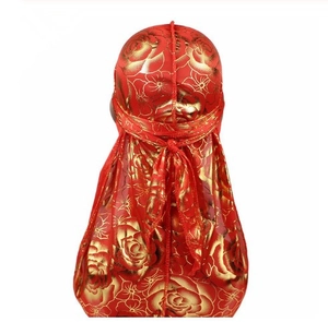 Detail view of red silky durag featuring golden rose patterns and long tail draping