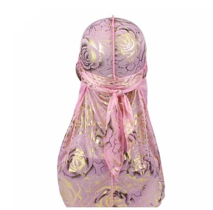 Detail of pink silky durag with gold floral pattern and long tail knotting on the back