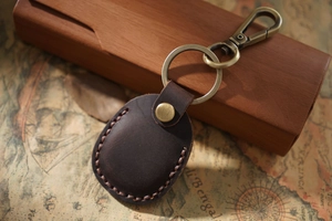 Close-up of vintage dark brown leather Airtag case with bronze keychain on retro map