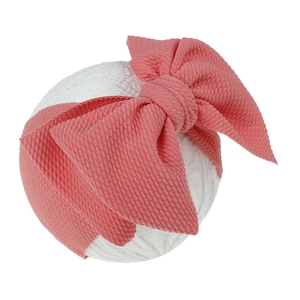 Pink baby headband with a large bow and ribbed texture shown on a white model head