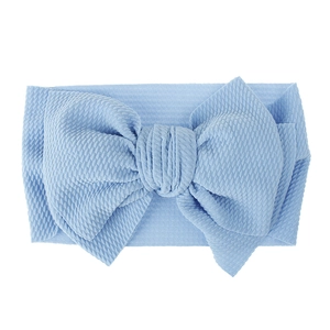 Close-up view of a light blue textured fabric baby headband featuring a large bow detail