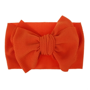 Detailed view of bright orange waffle knit fabric on a large bow baby headband