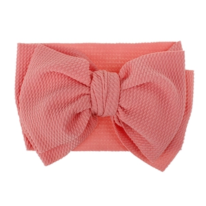 Detailed view of baby headband featuring coral waffle-textured knit fabric and large bow