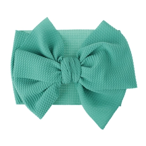 Macro detail of a mint green waffle textured fabric bow headband for babies and kids.