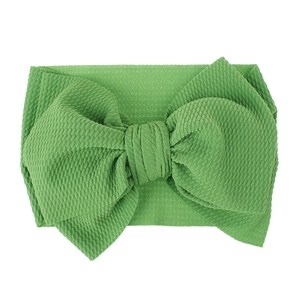 Detail of grass green waffle fabric baby headband with a large decorative bow