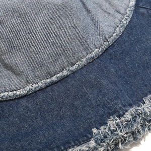 Gros plan macro du tissu denim à bords bruts et des coutures sur un chapeau bob
