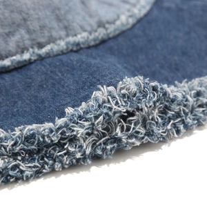 Vue macro des détails effilochés et de la texture sergé d'un bob en jean bleu