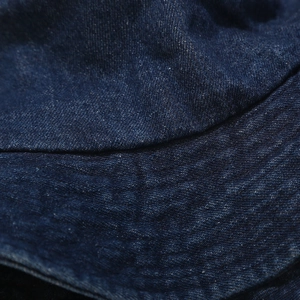 Vue macro détaillée de la texture du denim bleu foncé et des coutures précises sur le chapeau