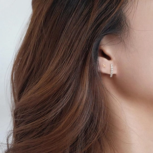 Elegant gold cactus stud and curved zirconia earring set on female model ear