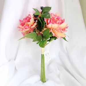 Artificial bridal bouquet with pink peony flowers, green leaves and black berries on white fabric