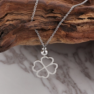 Detailopname van een zilveren klaverhanger ketting op rustiek hout en marmer