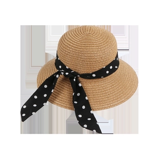 Detailed view of beige straw sun hat featuring a black polka dot ribbon and decorative bow