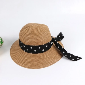 Detailed view of woven straw sun hat featuring a wide black and white polka dot bow